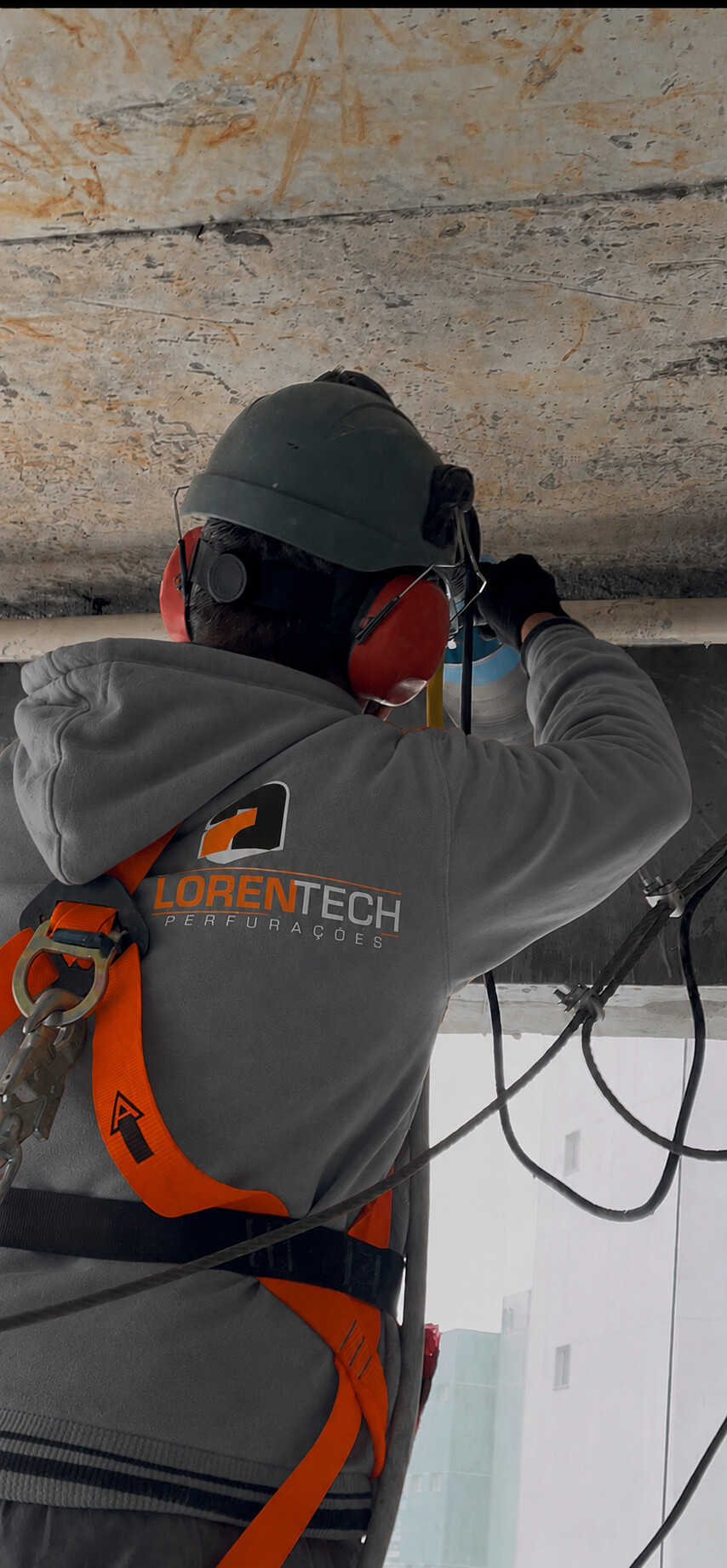 Operador da LorenTech realizando perfuração em viga de concreto com equipamentos de segurança